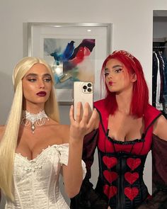 two women dressed up in costumes taking a selfie with their cell phones while standing next to each other