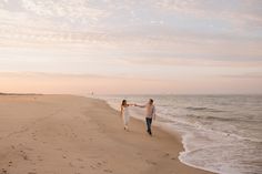 a man and woman walking along the beach holding hands