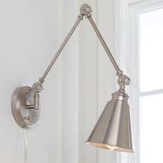 a wall light hanging from the side of a white wall with a window in the background