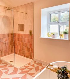 a bathroom with pink and white tiles on the floor, shower stall and sink area