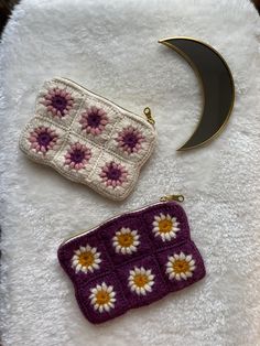 two crocheted purses sitting on top of a white towel next to a crescent