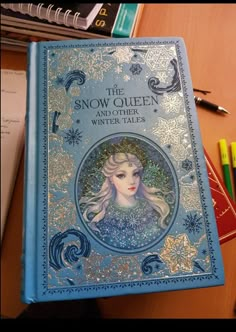 the snow queen and other winter tales on a desk with pens, books, and markers