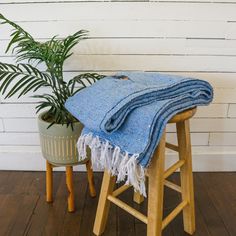 a blue blanket sitting on top of a wooden stool next to a potted plant