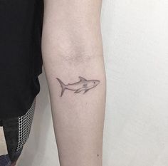 a small shark tattoo on the left arm