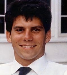 a man in a white shirt and tie smiling at the camera with his eyes wide open