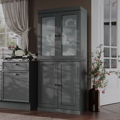 a kitchen with grey cupboards and white curtains on the window sill, next to a potted plant