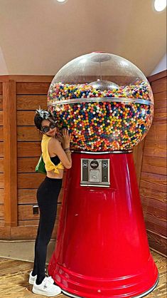 a woman standing next to a giant gummy machine