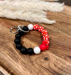 a red, white and black beaded bracelet sitting on top of a wooden table