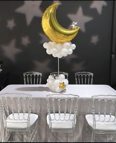 the table is set with white chairs and balloons in the shape of a crescent, stars and moon