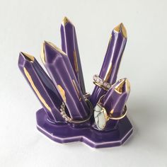 a purple and gold pen holder with rings on it's sides, sitting on a white surface