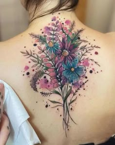 the back of a woman's shoulder with colorful flowers on her upper and lower back