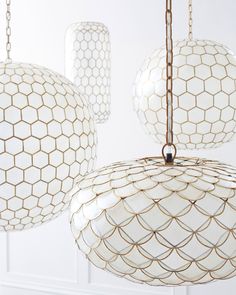 three white and gold chandeliers hanging from chains in a room with white walls