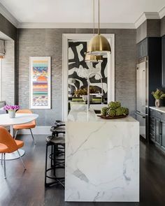 a kitchen with marble counter tops and orange chairs