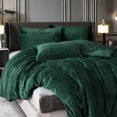 a bed with green comforter and pillows in a bedroom setting on top of a night stand