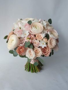 a bridal bouquet with pink and white flowers on a white background in front of a gray backdrop