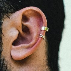 a man with an ear piercing is looking at the side of his head and has two gold rings on it