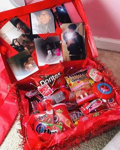 an open red box filled with candy and candies on top of a carpeted floor