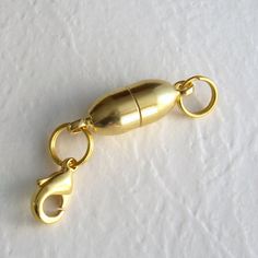 a close up of a gold colored object on a white surface with a chain attached to it