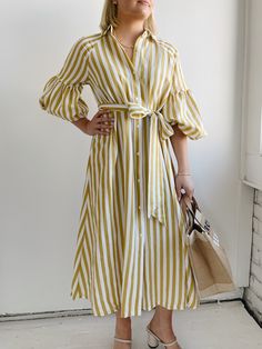 The Ischia Stripe Dress is a shirt dress with flair. Featuring a button down front, shirt collar, tie belt and drop shoulder to an oversized bubble sleeve and pockets. Pair with white tennis shoes or a pair of nude sandals to complete a perfect summer look. Fit: True to sizeFabric Content: 80% Rayon 20% NylonFabric Care: Machine Wash Cold Gentle Cycle, lay flat to dryMeasurements: 45" Shoulder to hemLining: NoZipper: No S:0-2 M:4-6 L:8-10 Yellow Striped Dress, White Tennis Shoes, Nude Sandals, York Dress, Bubble Sleeve, Mother Denim, Stripe Dress, Summer Look, Yellow Stripes