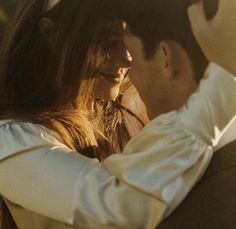 a man and woman embracing each other in front of the camera with their arms around one another