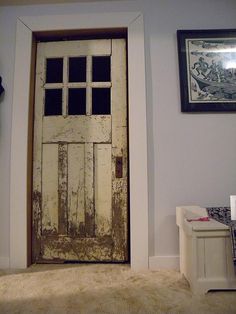 an old white door in a room with pictures on the wall and carpeted floor