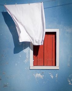 an open red door on a blue wall with a white cloth hanging from it's side