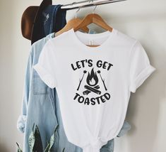 Lets Get Toasted Shirt, Camping Shirt, Hiking Shirt, Funny Camper Shirt, Camp Shirt Women, Camp Shirt Men, Camping Gift, Family Camp Shirt, Adventure tee, , Campfire shirt, Gift For Her, Gift For Him GUIDANCE *All our simple color t-shirts are 100% Cotton. *All our Heather Color t-shirts are 90% cotton 10% polyester blend and they are extremely soft. Our design are made very professionally with the right equipment *Soft and High-Quality Fabric *Taped shoulder-to-shoulder *Tear away label *Retail fit *Pre-shrunk * Side Seamed *Design size and placement is approximate. Each shirt is custom hand made exact size and placement of design may vary. FONTS AND DESIGN *Due to monitor differences, actual colors may vary slightly from what appears online. *You can choose your text color from the list Casual Camp Shirt With Funny Print, Men Camping, Casual Pre-shrunk Camp Shirt For Camping, Custom Print Crew Neck T-shirt For Camping, Pre-shrunk Cotton Camp Shirt For Camping, Affordable Relaxed Fit T-shirt For Camping, Camper Shirt, Hiking Shirt, Camp Shirt