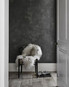 a chair sitting in front of a black and white wall with a book on the floor