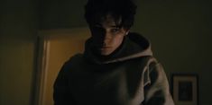 a young man wearing a hoodie in the dark