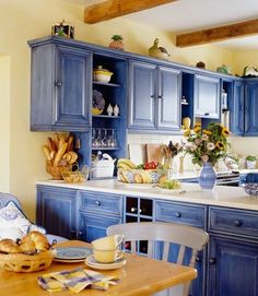 a kitchen with blue cabinets and white counter tops in front of a window filled with sunflowers