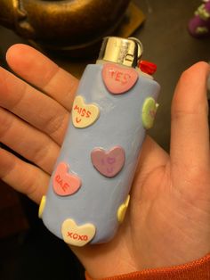 a hand holding a blue lighter with hearts on it and the words yes written on it