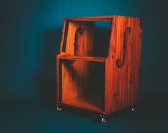 a wooden shelf with wheels on it against a blue wall