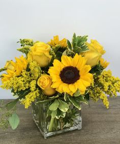 a vase filled with yellow flowers on top of a wooden table