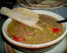 a white bowl filled with soup and a piece of bread sticking out of the top