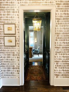 an entry way leading to a living room and dining room with patterned wallpaper on the walls