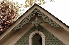 a green and white building with a clock on it's front window, next to a tree