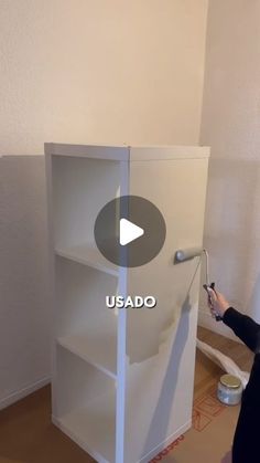 a woman is painting the side of a white bookcase with an ad that reads usado