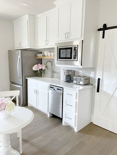 a kitchen with white cabinets and stainless steel appliances is pictured in this image, there are flowers on the counter