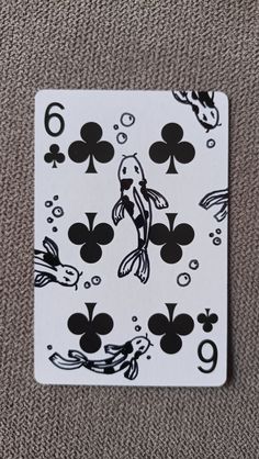 a playing card that has fish and spades on it, sitting on the ground