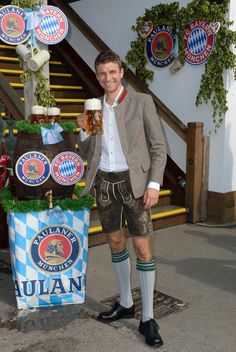 a man standing in front of a sign with beer on it and decorations around him