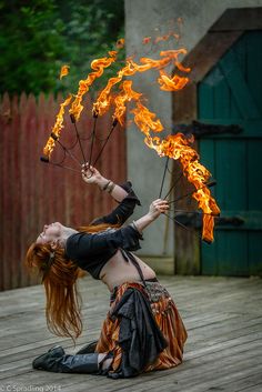 a woman with red hair is holding fire sticks