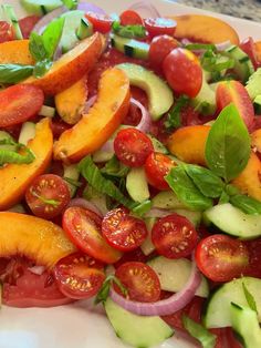 a salad with tomatoes, cucumbers, and other veggies on it