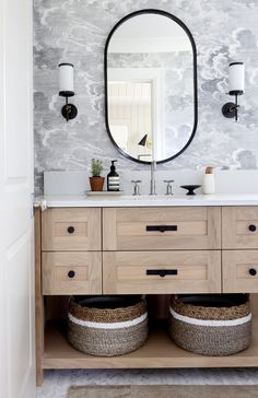 a bathroom vanity with two baskets under the sink and a large mirror above it,