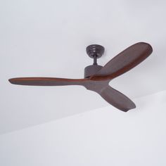 a ceiling fan mounted on the side of a wall in a room with white walls