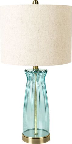 a blue glass table lamp with a gold base and white linen shade on the top