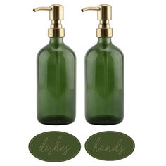 two green glass soap dispenser bottles with brass handles and labels on them