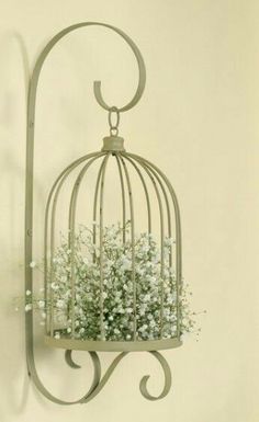 a birdcage filled with baby's breath flowers hanging from a hook on a wall