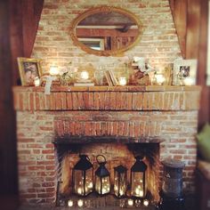 a fireplace with candles and pictures on it