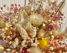 a bunch of flowers that are sitting on a table in front of a white wall