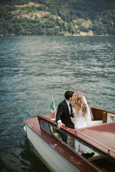 a bride and groom in a small boat on the water with a flag sticking out of it's side